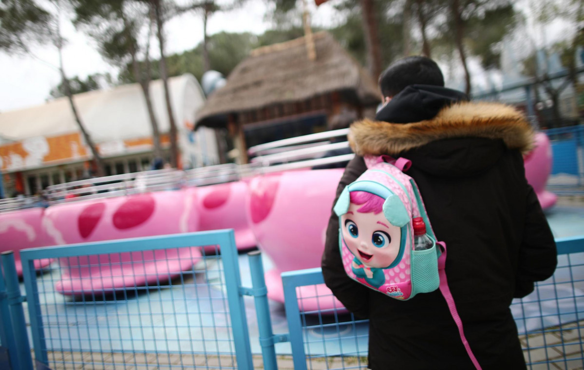 Archivo - Un hombre con una mochila infantil en el Parque de Atracciones.