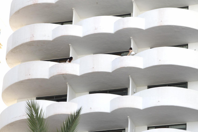 Archivo - Dos jóvenes en un balcón del hotel Palma Bellver, donde estaban confinados los estudiantes.