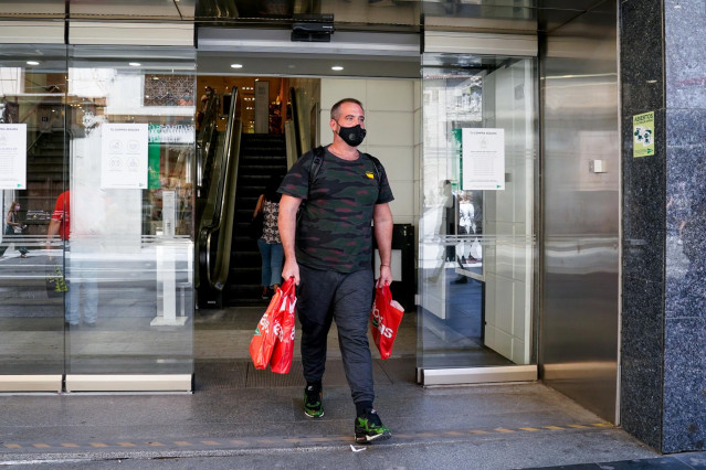 Archivo - Un hombre sale con varias bolsas de un establecimiento de la capital en plenas rebajas de verano