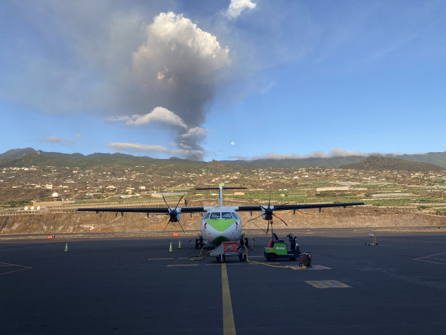 Un avión de Binter en la pista del aeropuerto de La Palma, con el volcán en erupción al fondo
