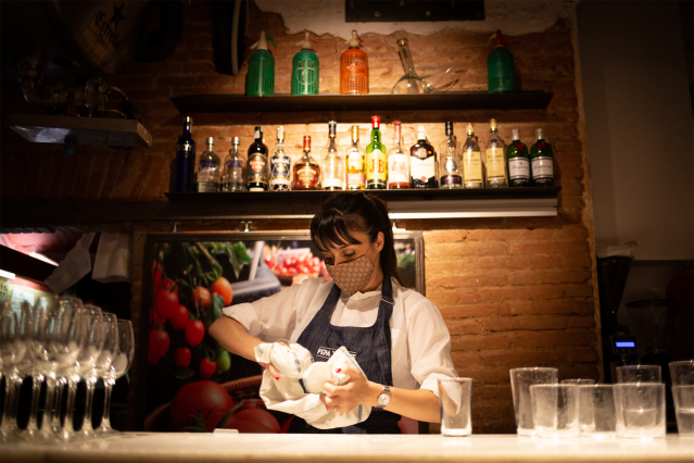 Una camarera seca unos vasos en el interior de un bar en una calle céntrica de Barcelona, a 14 de octubre de 2021, en Barcelona.