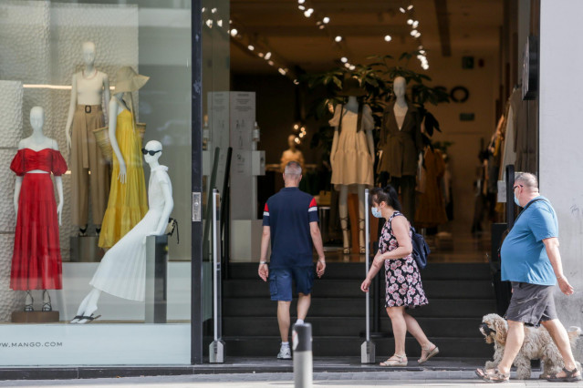 Archivo - Varias personas entran a una tienda de moda