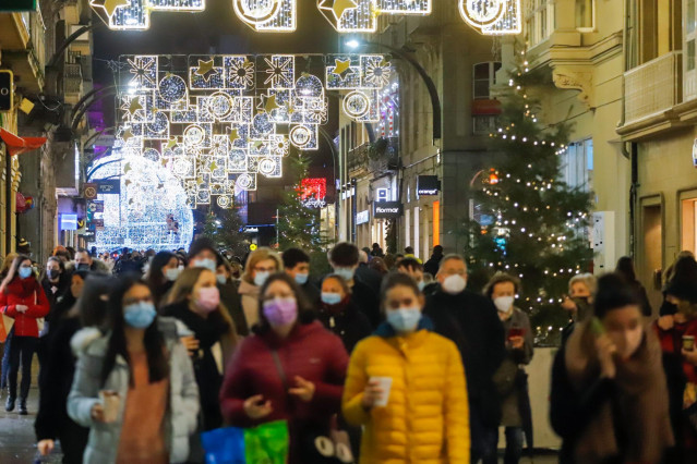 Archivo - Varias personas pasean por calles comerciales en Navidad