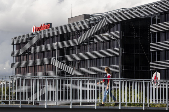 Archivo - Una persona camina al lado de la sede de Vodafone en Madrid