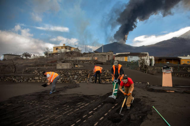 Varios voluntarios trabajan retirando cenizas de los tejados de varias casas próximas al volcán de Cumbre Vieja, a 5 de noviembre de 2021, en La Palma, Canarias (España). Estos voluntarios retiran de los tejados de las casas y sus alrededores los metros d