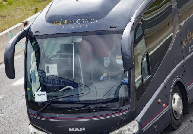 Archivo - Un conductor de autobús totalmente protegido conduce por una carretera madrileña