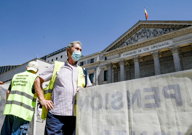 Archivo - Un hombre sostiene una pancarta durante una concentración de pensionistas frente al Congreso, en una imagen de archivo