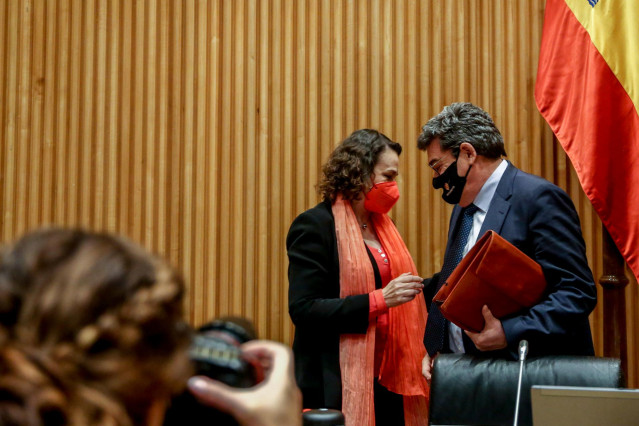 El ministro de Inclusión, Seguridad Social y Migraciones, José Luis Escrivá (d), habla con la presidenta de la Comisión de Seguimiento y Evaluación de los Acuerdos del Pacto de Toledo, Magdalena Valerio (i), antes de comparecer en la comisión