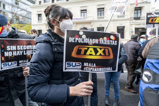 Una mujer con un cartel en el que se lee 'De policías a taxistas', en una concentración contra la reforma de la ‘Ley Mordaza’ frente a la Delegación del Gobierno en Madrid