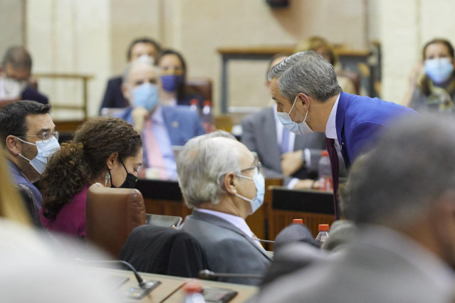 El consejero de Hacienda y Financiación Europea, Juan Bravo, (d) se acerca al escaño de la portavoz de l grupo parlamentario Unidas Podemos, Inmaculada Nieto, (i) durante el Debate de Presupuesto de la Junta de Andalucía, a 24 de noviembre de 2021 en el P