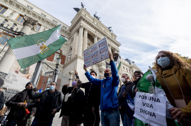 Un grupo de personas con la bandera de Andalucía participa en una concentración de agricultores y exportadores de naranjas, frente al Ministerio de Agricultura