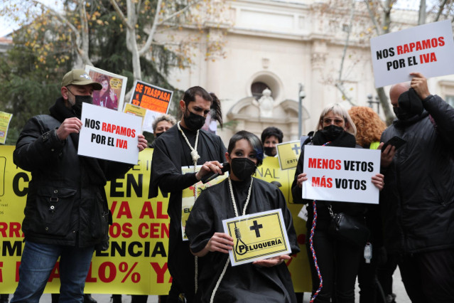 Un hombre rapa a una mujer durante una protesta de profesionales de peluquería y estética, frente al Senado, a 9 de diciembre de 2021, en Madrid (España). Durante la protesta, trabajadores y trabajadoras se han rapado el pelo para reclamar que el proyecto
