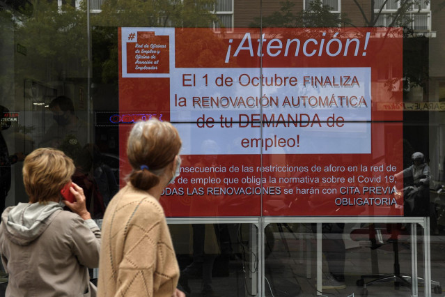 Archivo - Varias personas observan un anuncio de una Oficina del Servicio Público de Empleo Estatal (SEPE), en una imagen de archivo.