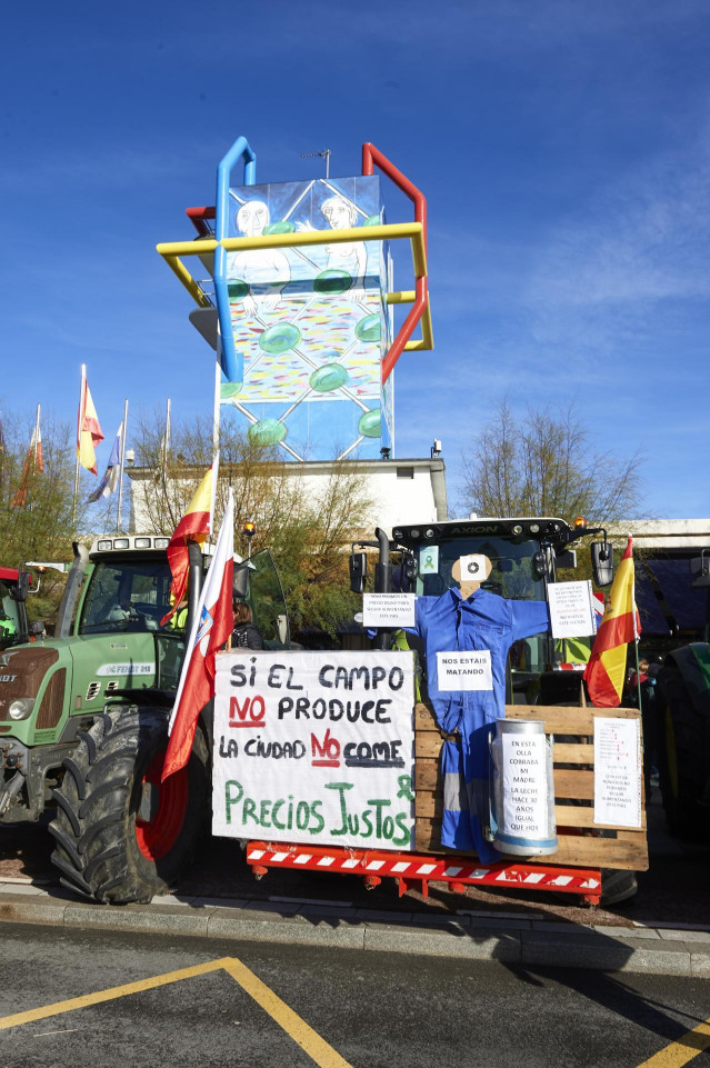 Un tractor sostiene un palé con una pancarta en la que se lee 
