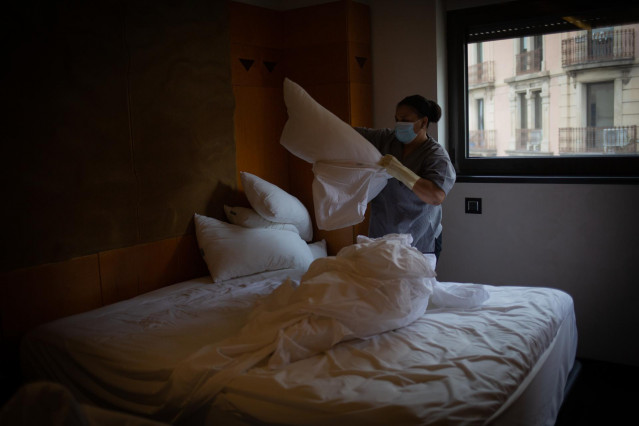 Archivo - Una camarera de pisos cambia las sábanas de una cama de una habitación.