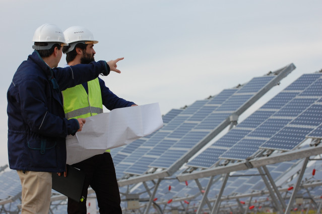 Dos operarios debaten en un parque fotovoltaico.