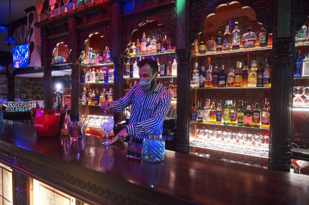 Archivo - Un trabajador prepara una copa en la barra de un bar
