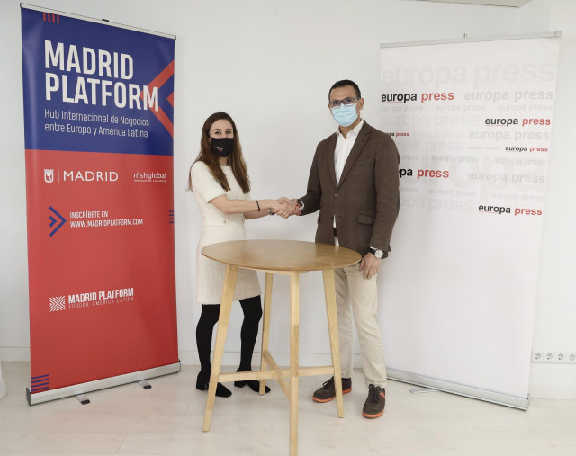 La directora de desarrollo de negocio de Europa Press, Candelas Martín de Cabiedes, y el presidente de Madrid Platform, Carlos Morales, se dan la mano tras firmar un convenio entre Europa Press y  Madrid Platform en las oficinas de la agencia de noticias,