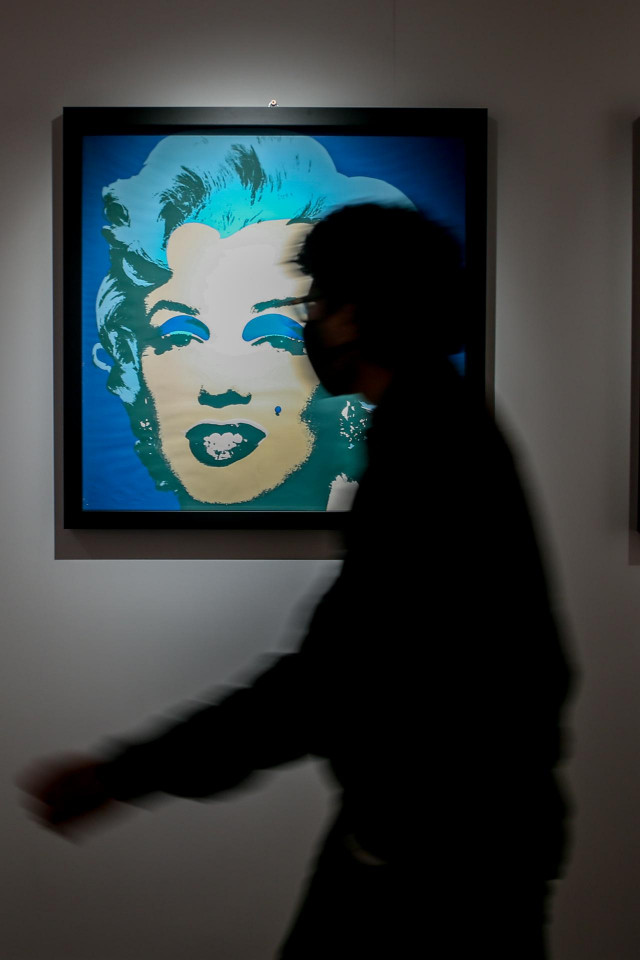 Una persona para por delante de un retrato de Marilyn Monroe,   en la inauguración de la exposición 'ANDY WARHOL SUPER POP', en el Palacio de Santa Bárbara, a 11 de febrero de 2022, en Madrid (España).