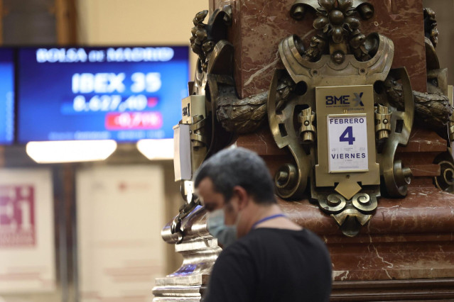 Un hombre delante de un panel con valores del Ibex 35.