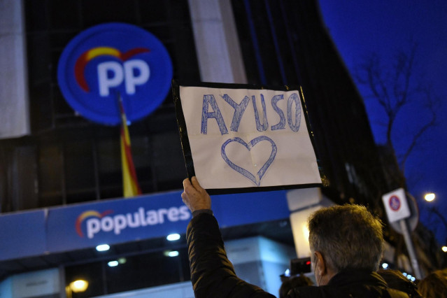 Un hombre sostiene un cartel en el que se lee Ayuso con un corazón, durante una manifestación en apoyo a la presidenta de la Comunidad de Madrid, Isabel Díaz Ayuso, frente de la sede del Partido Popular en la calle Génova.