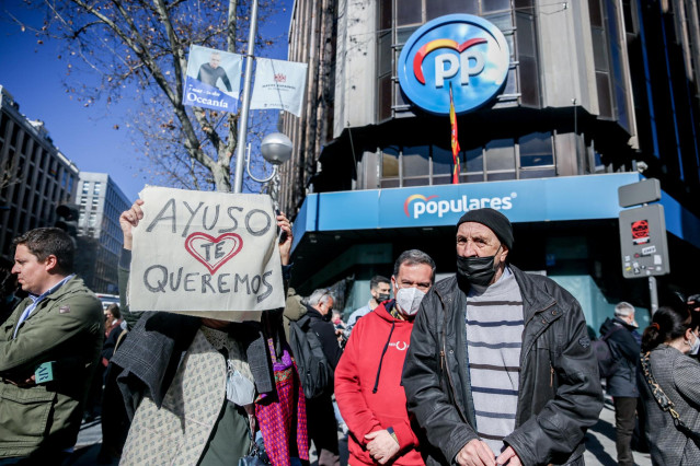 Varias personas, con una pancarta que reza, 'Ayuso te queremos' en una concentración de apoyo a Díaz Ayuso, en la sede del Partido Popular, a 20 de febrero de 2022, en Madrid (España).