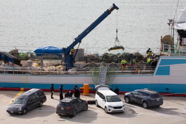 Operarios bajan con la ayuda de una grúa a uno de las personas fallecidas en el naufragio del buque gallego, a su llegada al Puerto de San Juan de Terranova, a 19 de febrero de 2022, en San Juan, Terranova (Canadá).