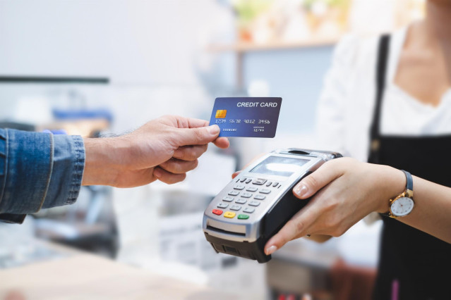 Archivo - Una persona pagando con tarjeta de crédito en un datafono de un comercio