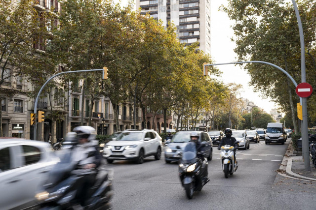 Coches y motos circulan por una calle de Barcelona con tráfico.