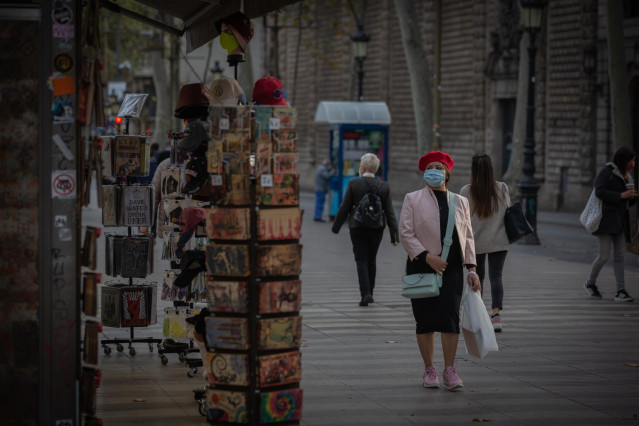 Archivo - Una mujer frente a una tienda de artículos turísticos en Barcelona, Catalunya (España).