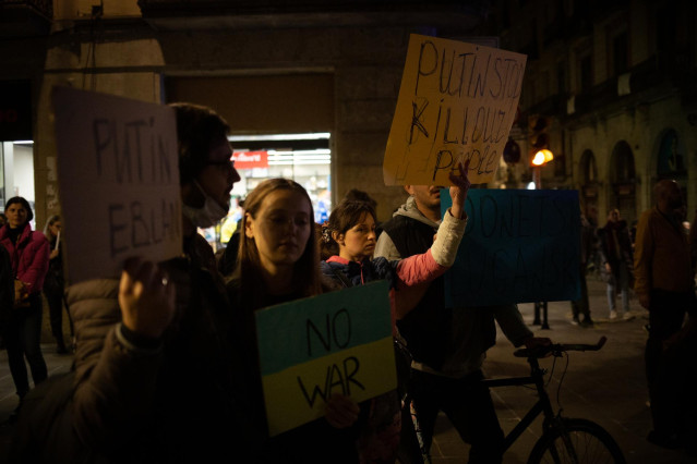 Varias personas sostienen pancartas en una concentración ante la embajada rusa en Barcelona tras los primeros ataques rusos registrados en Ucrania esta pasada madrugada, a 24 de febrero de 2022, en Barcelona, Cataluña (España).