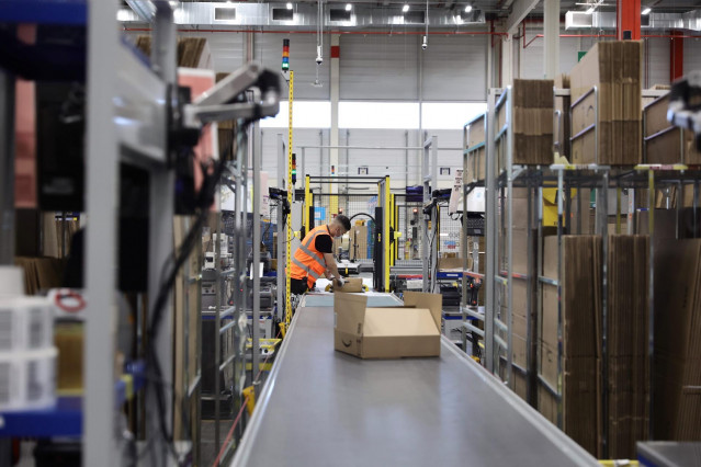 Un trabajador empaqueta pedidos en cajas de cartón en la sede de Amazon en Alcalá de Henares, Madrid (España).