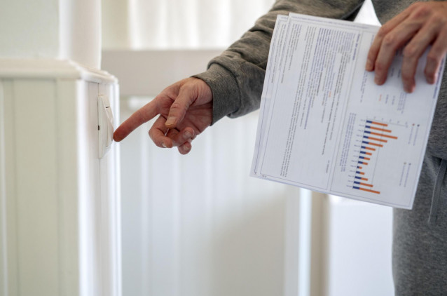 Archivo - Un hombre enciende un interruptor con una factura de luz en la mano, a 3 de enero de 2022, en Madrid, (España)