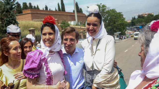 El alcalde de Madrid, José Luis Martínez-Almeida, se fotografía con dos chulapas a su llegada a la popular misa de campaña en la explanada de las inmediaciones de la Ermita de San Isidro