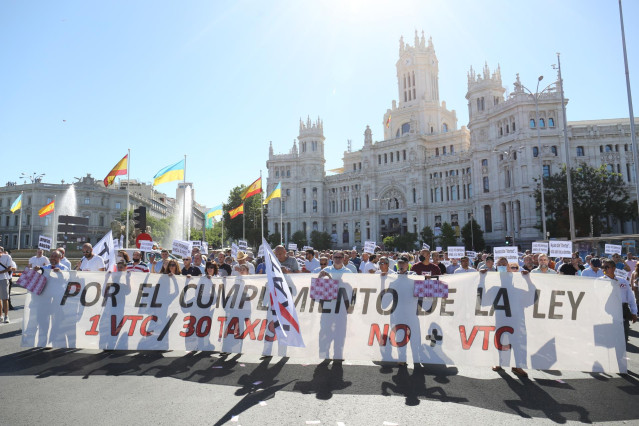 Varias personas sujetan una pancarta en la que se lee: 'Por el cumplimiento de la ley 1 VTC/ 30 taxis, no + VTC', durante una marcha contra la reforma de la Ley de Transportes, a 1 de junio de 2022, en Madrid (España). La Federación Profesional del Taxi d