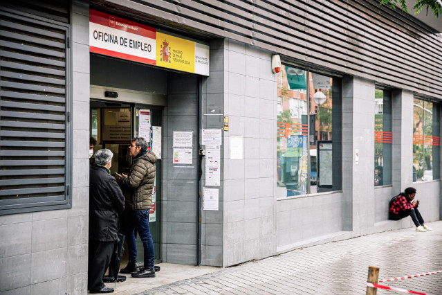 Archivo - Varias personas en la entrada de una oficina de empleo