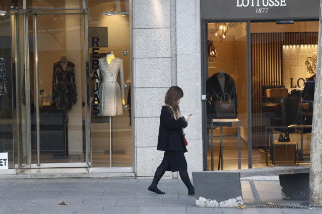 Archivo - Una mujer pasa por un centro comercial de Madrid en período de rebajas.