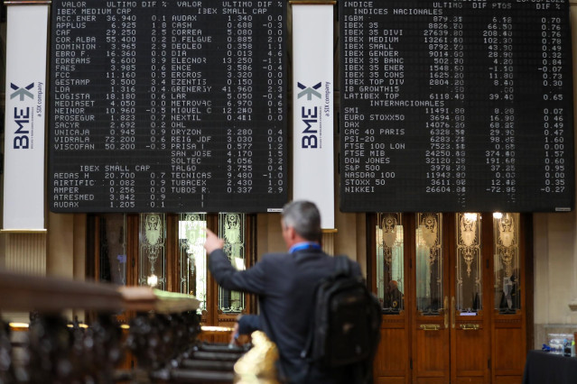Un hombre señala los paneles de valores del IBEX 35 en el Palacio de la Bolsa de Madrid, a 26 de mayo de 2022, en Madrid (España).