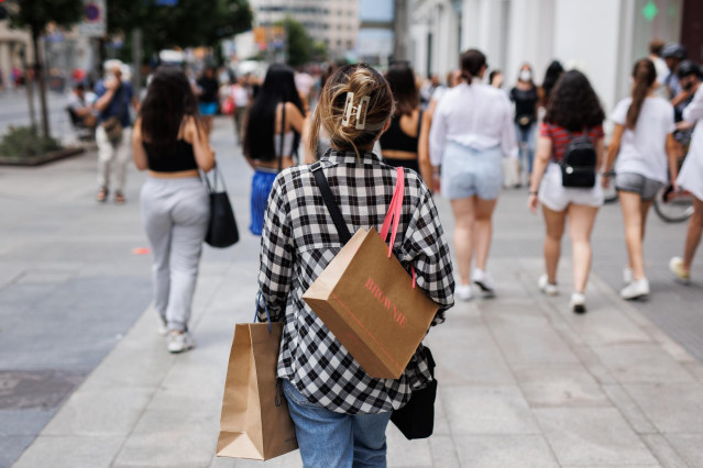 Una mujer pasea con bolsas de firmas de moda por la Gran Vía, a 21 de junio de 2022, en Madrid (España).