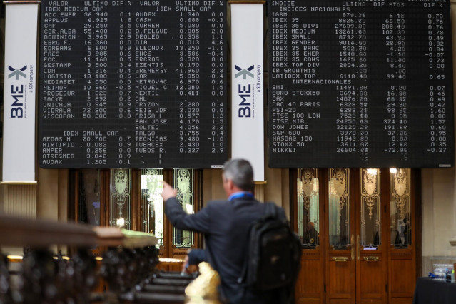 Un hombre señala los paneles de valores del IBEX 35 en el Palacio de la Bolsa de Madrid