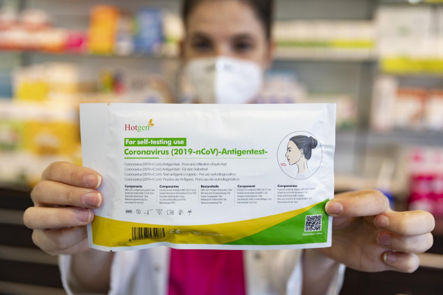 Archivo - Una farmacéutica muestra un test de antígenos