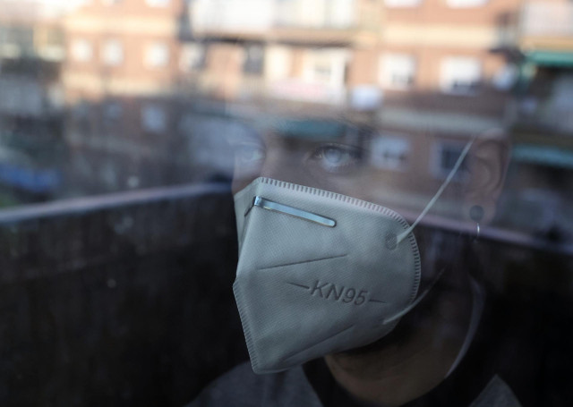 Archivo - Una persona con mascarilla en su domicilio, a 29 de diciembre de 2021, en Madrid (España). Sanidad y las comunidades autónomas han llegado a un acuerdo unánime para reducir la cuarentena de los positivos por Covid-19 de díez a siete días, tras l