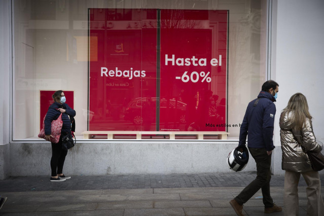 Archivo - Varias personas pasan delante de un escaparate con cartel de rebajas en una calle comercial del centro de Madrid, a 2 de enero de 2022, en Madrid, (España). Comienzan las rebajas de enero que generarán un 14 % más de empleo, sobre todo en logíst