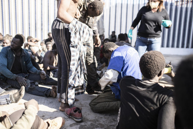Archivo - Varios migrantes tras saltar la valla en Melilla