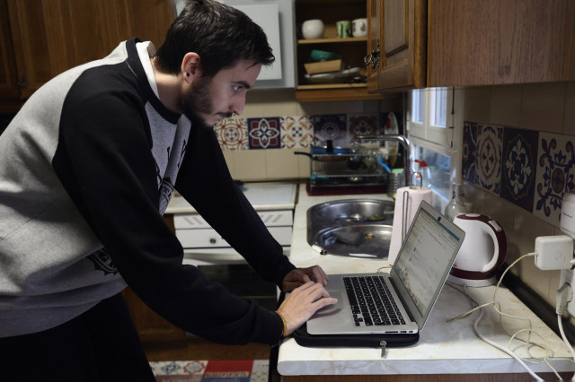 Archivo - Una persona teletrabajando en la cocina de su domicilio