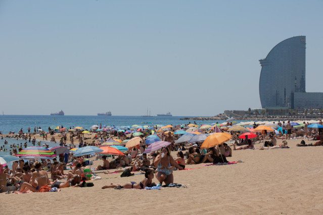 Varias personas se protegen del sol en la playa de la Barceloneta, en una imagen de archivo.