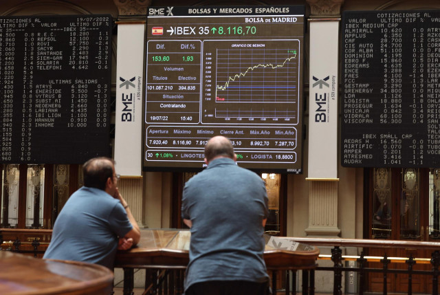 Dos personas miran los paneles del Palacio de la Bolsa, a 19 de julio de 2022, en Madrid (España).