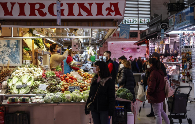 Archivo - Varias personas compran en un puesto de fruta y verdura en el Mercado Central de Valencia