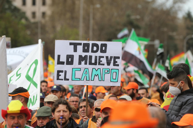 Archivo - Varios manifestantes, con gorras naranjas con una pancarta que reza 'Todo lo mueve el campo', durante la  la marcha por el mundo rural ‘20M’ en Madrid