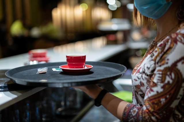Archivo - Una trabajadora lleva un café durante una jornada marcada por la reapertura de los establecimientos en los municipios vascos pertenecientes a la ‘zona roja’, en Vitoria, Álava, País Vasco, (España), a 10 de febrero de 2021. La reapertura se prod